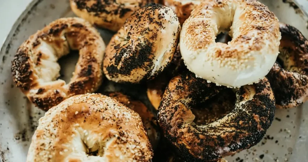 Freshly baked bagels topped with sesame seeds and poppy seeds, arranged on a rustic platter